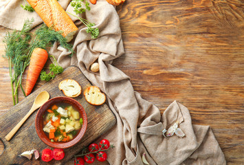 Bowl of tasty soup with vegetables and bread on wooden table