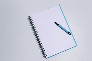 White clean notebook with blue crayon