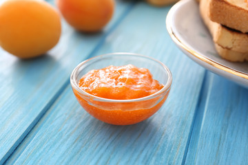 Bowl of tasty apricot jam on table