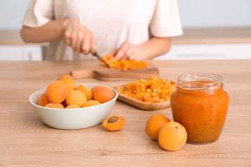 Obraz na płótnie Canvas Woman preparing tasty apricot jam at table
