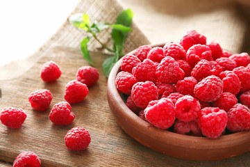 Plate with fresh raspberries on table