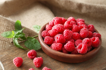 Plate with fresh raspberries on table