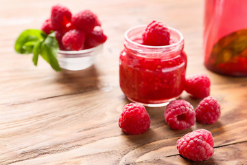 Jar of raspberry jam on wooden table