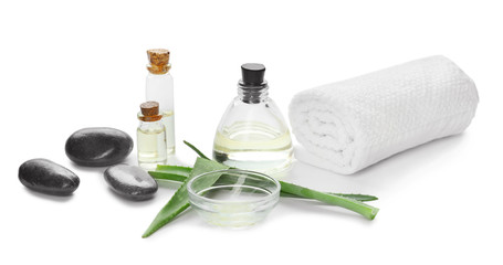 Fresh aloe leaves with essential oil, spa stones and towel on white background