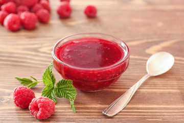 Bowl of tasty raspberry jam on wooden table