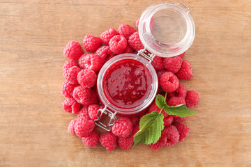 Jar of tasty raspberry jam on wooden table