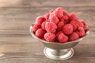 Bowl with fresh raspberries on wooden table