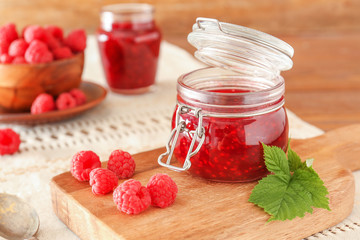 Jar of tasty raspberry jam on table