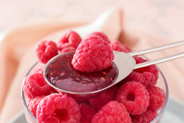 Glass with fresh raspberries and spoon with jam, closeup