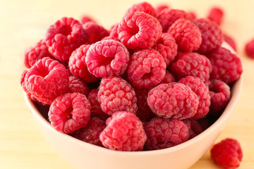 Bowl with fresh raspberries on table, closeup