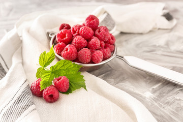Sieve with fresh raspberries on table