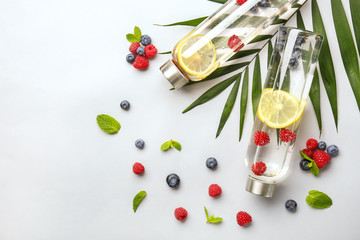 Bottles of tasty infused water on light background