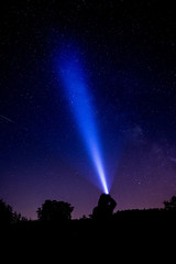 Fototapeta na wymiar Silhouette einer Person die die Milchstraße mit einer Taschenlampe anleuchtet