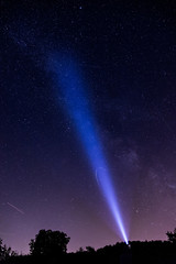 Milchstraße mit Sternenhimmel wird mit einer Taschenlampe angestrahlt