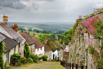 Stone houses along the steep cobbled street of Gold Hill in Shaftsbury England with view of farm...