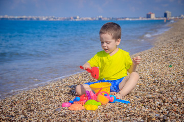 The boy plays on the beach in the toys for the sand. Children's games. Games on the beach. Galichny beach. Children's toys for sand. The baby is playing