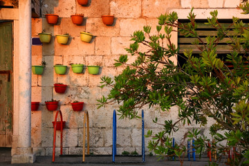 Historical stone building decorated with colorful flower pots, in small town Sutivan, on island Brac, Croatia. Illuminated by warm sunset light.