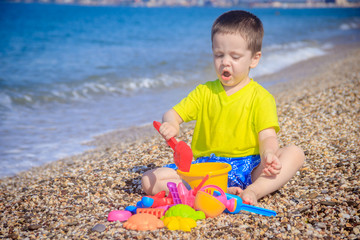 The boy plays on the beach in the toys for the sand. Children's games. Games on the beach. Galichny beach. Children's toys for sand. The baby is playing
