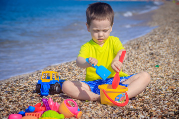 The boy plays on the beach in the toys for the sand. Children's games. Games on the beach. Galichny beach. Children's toys for sand. The baby is playing