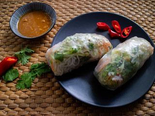 Nem song on a plate with cilantro and half pepper on a wicker background