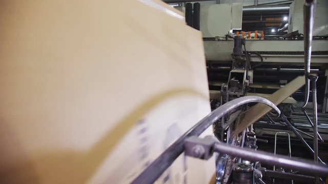 machine bends cardboard for boxes with logo in workshop