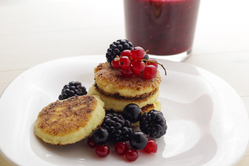 Cottage cheese pancakes or syrniki with fresh berries on plate, close up