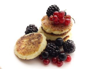 Cottage cheese pancakes or syrniki with fresh berries on plate, close up