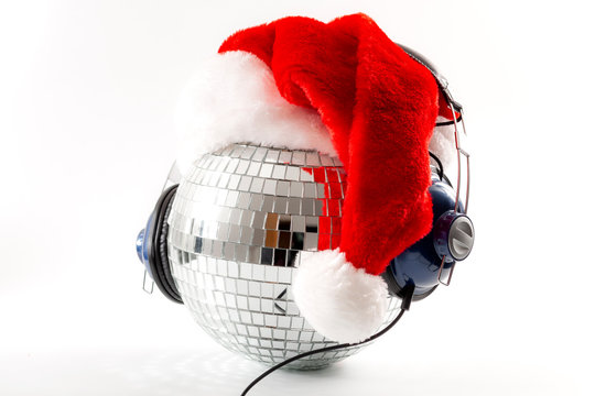 Merry Christmas, Happy Occasion And New Year Eve Party Poster Concept With A Shiny Silver Disco Ball Covered In Mirror Glass Wearing A Santa Claus Hat And Headphones Isolated On White Background