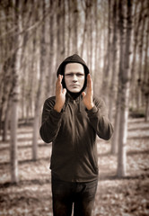 Hooded mysterious man with mask in the woods