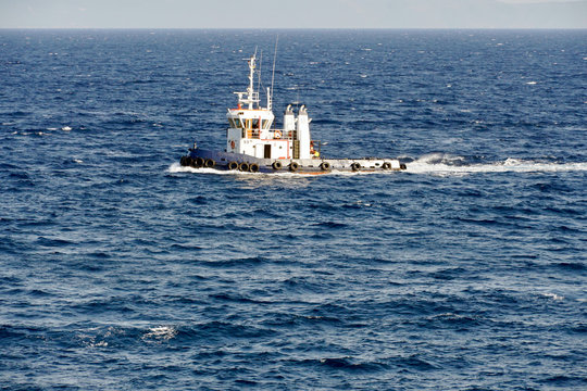 Tug Boat In Open Water And Choppy Sea Is Heading To Escort A Nearby Ship