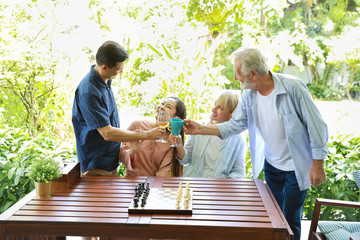 group of multiethnic senior people playing chess board while clinking glasses with happy smiling face on holiday vacation