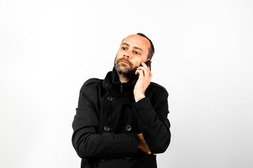 Middle-aged man with overcoat listens attentively to a conversation on his mobile phone, isolated...