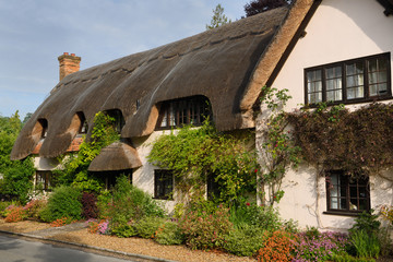 Fototapeta na wymiar Thatched roof house with flower garden in morning sun at West Amesbury Salisbury England