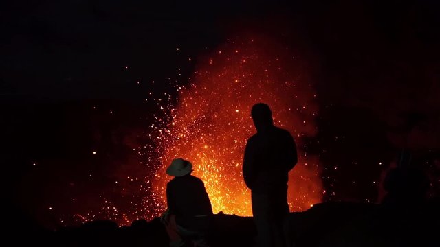 Volcanic Eruption and Adventurers Closeup Slowmotion. Silhouettes of People Over Volcano Crater With Burning Lava