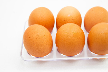 brown Eggs have water droplets in plastic box on white background.