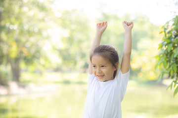 Beautiful young asian child smiling and cheerful playing at park, asia kid confident jump and fun in the garden activities outdoor at garden in nature summer, lifestyle concept.