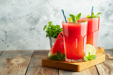 Watermelon slushie with lime and mint, summer refreshing drink in tall glasses on a light blue background. Sweet cold smoothie with copy space