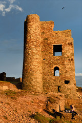 Girl with dogs and puppy at ruins of Stamps and Whim Engine house at Wheal Coates tine mine in red light at sunset Cornwall England