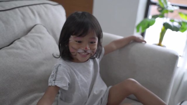 happy asian mom painting her kids in the face at livingroom