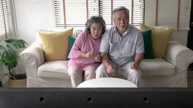 Senior couple watching movie excite emotion together at home. Concept of technology, entertainment and cinema. 4k resolution.