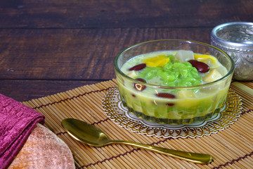 Cendol is an iced sweet dessert, contains droplets of green pandan rice flour jelly, mixed with red beans, sliced jackfruit, coconut jelly and others in coconut milk and palm sugar syrup. Copy space.