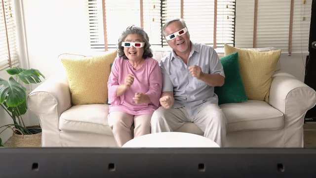 Senior couple watching movie excite emotion together at home. Senior man and woman wearing 3d glasses. Concept of technology, entertainment and 3d movie. 4k resolution.