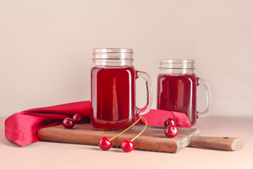 Mason jars of tasty cherry juice on light table