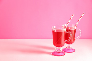 Glass cups of tasty cherry juice on color background