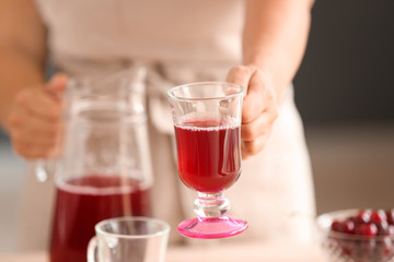 Woman holding glass cup with tasty cherry juice, closeup