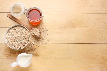 Obraz na płótnie Canvas Bowl with raw oatmeal, honey and milk on wooden table