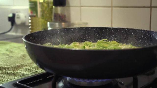 MCU Sliced leeks are being sauteed in butter, and stewed inside a large steaming pan.
