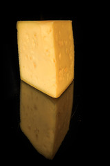 vertical view of hard porous yellow cheese piece with holes