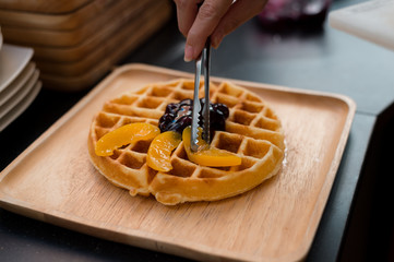 waffles topping peach and ice cream on wooden plate