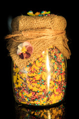 closeup glass jar with different shaped colorful topping